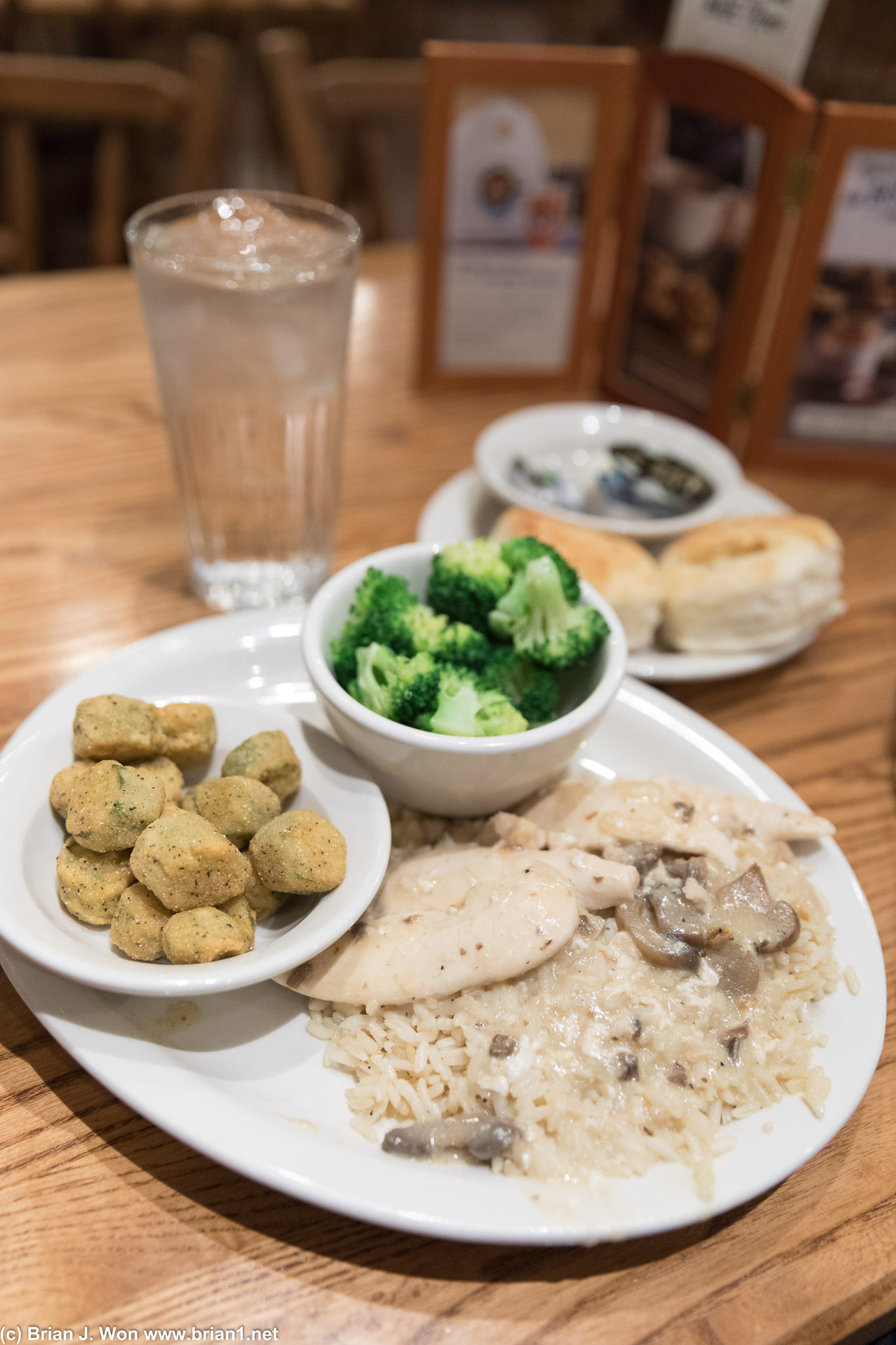 Chicken and rice with fried okra, broccoli, and biscuits.