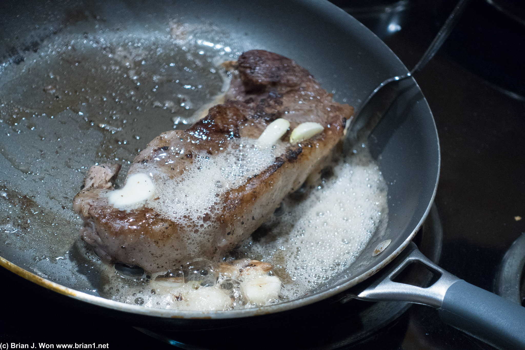 Sous vide steak being seared with butter and garlic.