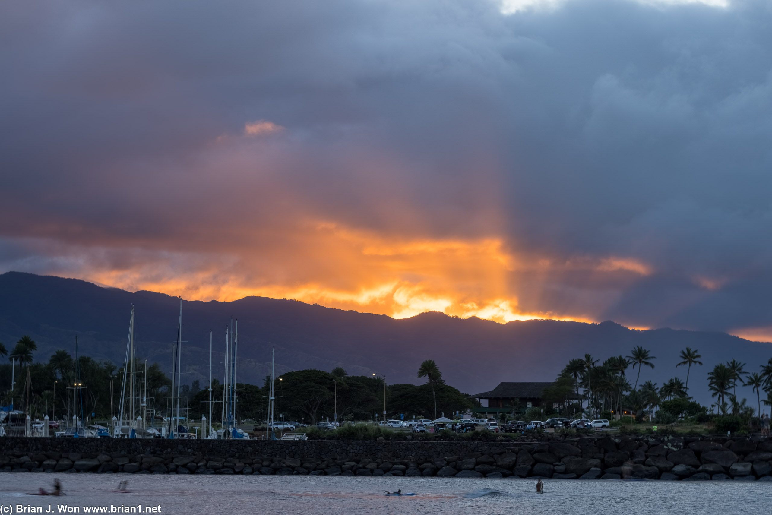 Hale'iwa harbor in the foreground as clouds threaten to extinguish the sunset.