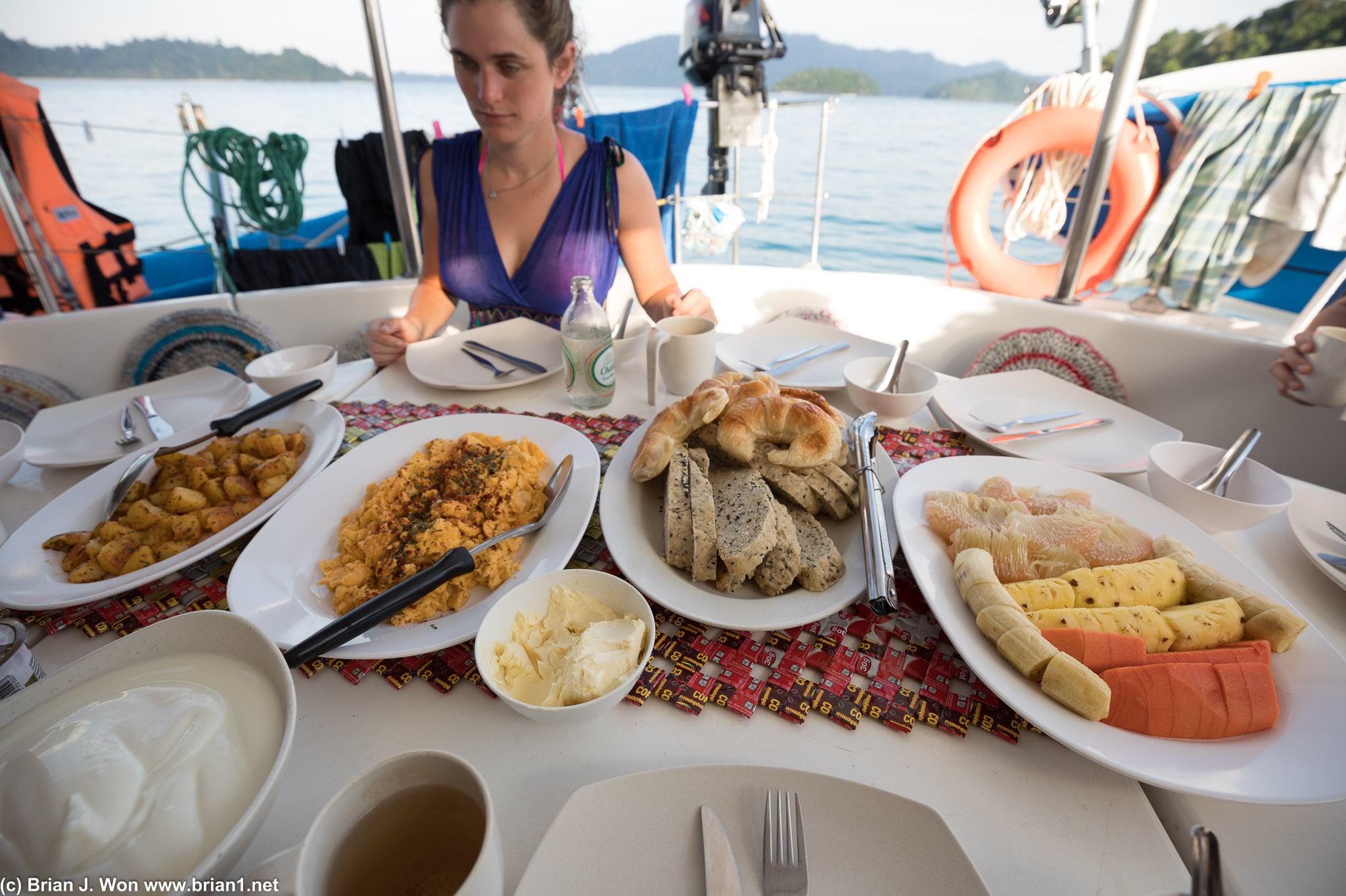 Potatoes, scrambled eggs, bread, fruit, and yogurt for breakfast.