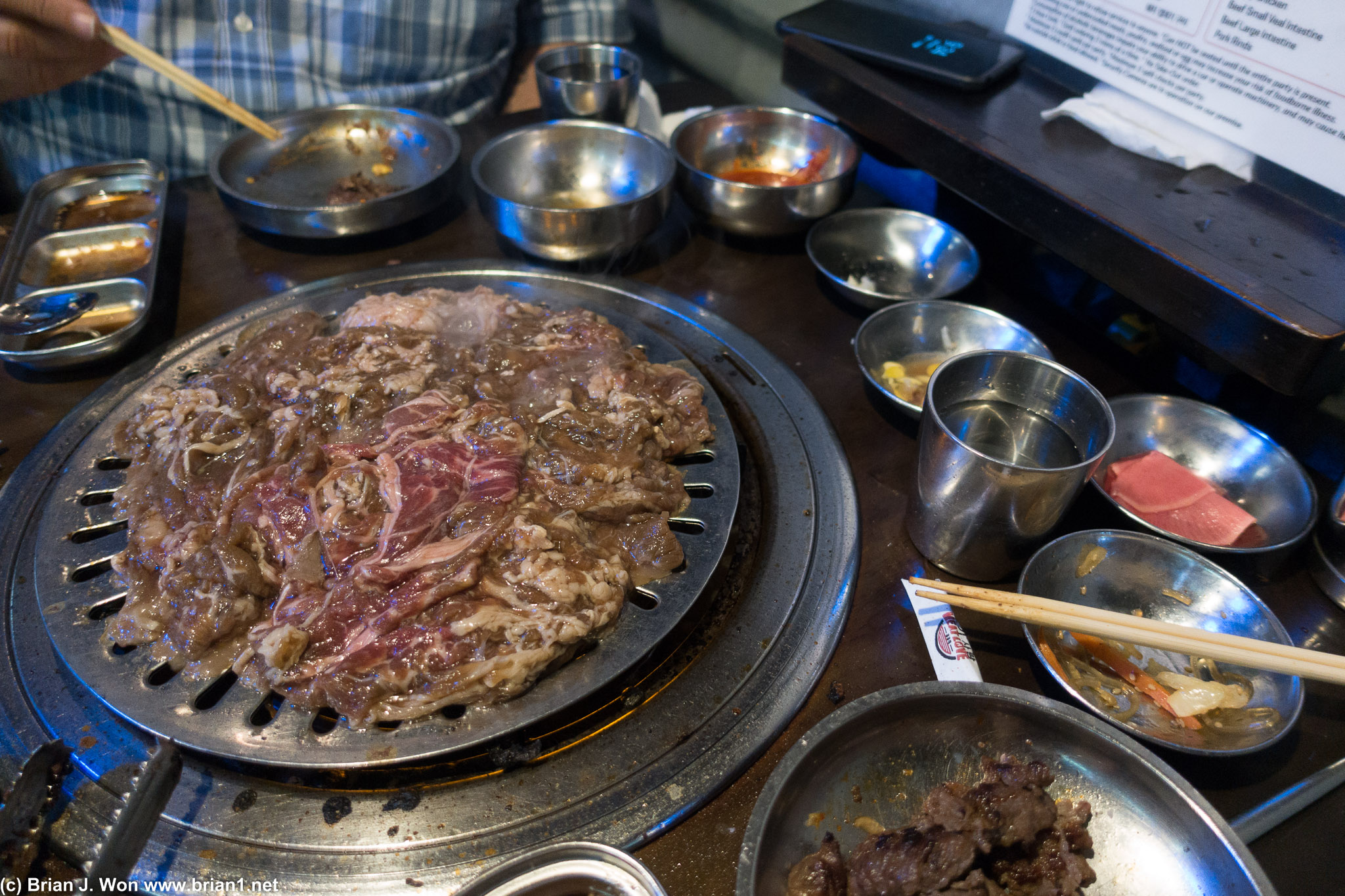 A grill full of marinaded bulgogi and a table full of empty ban chan.