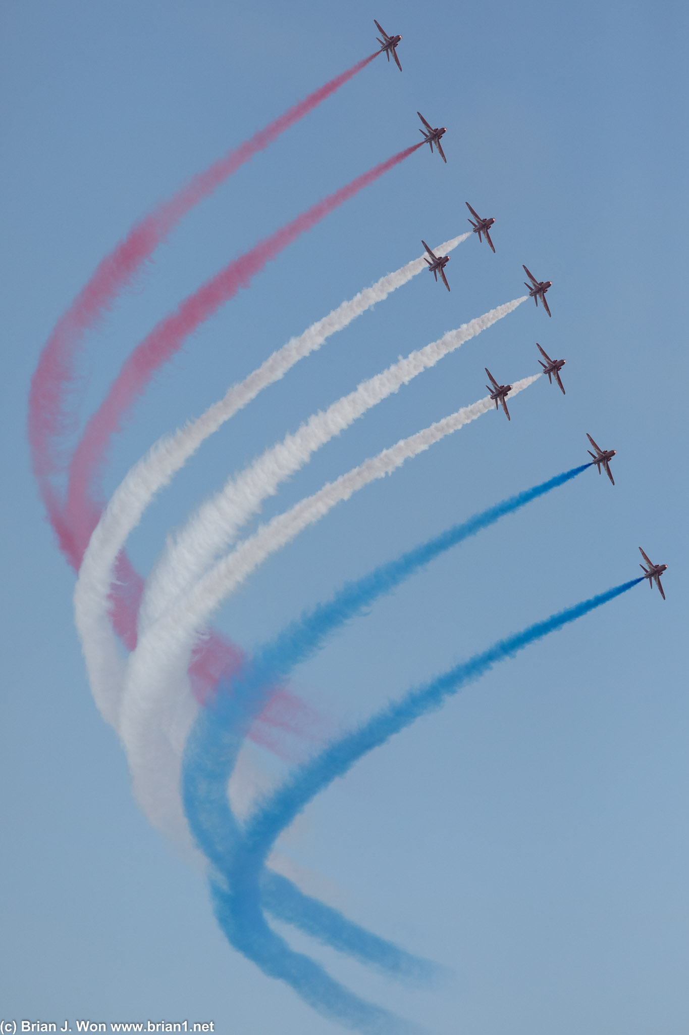 Swooping formation of red, white and blue by the RAF Red Arrows.