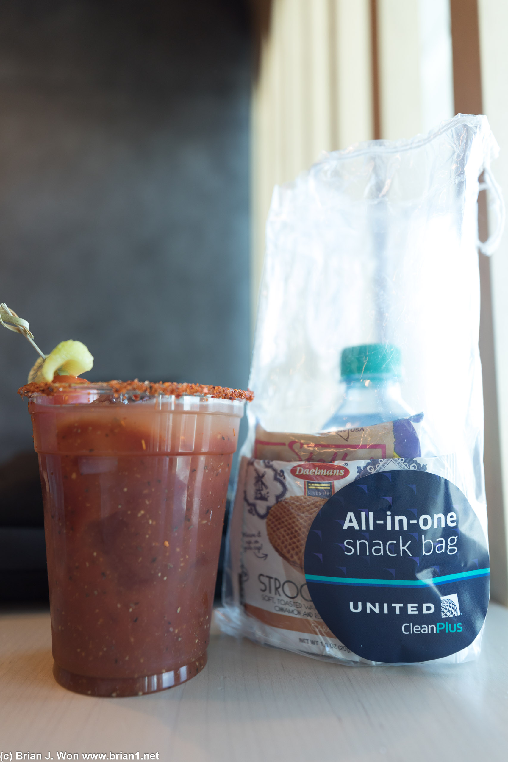 Bloody mary on left, United first class snack bag at right.