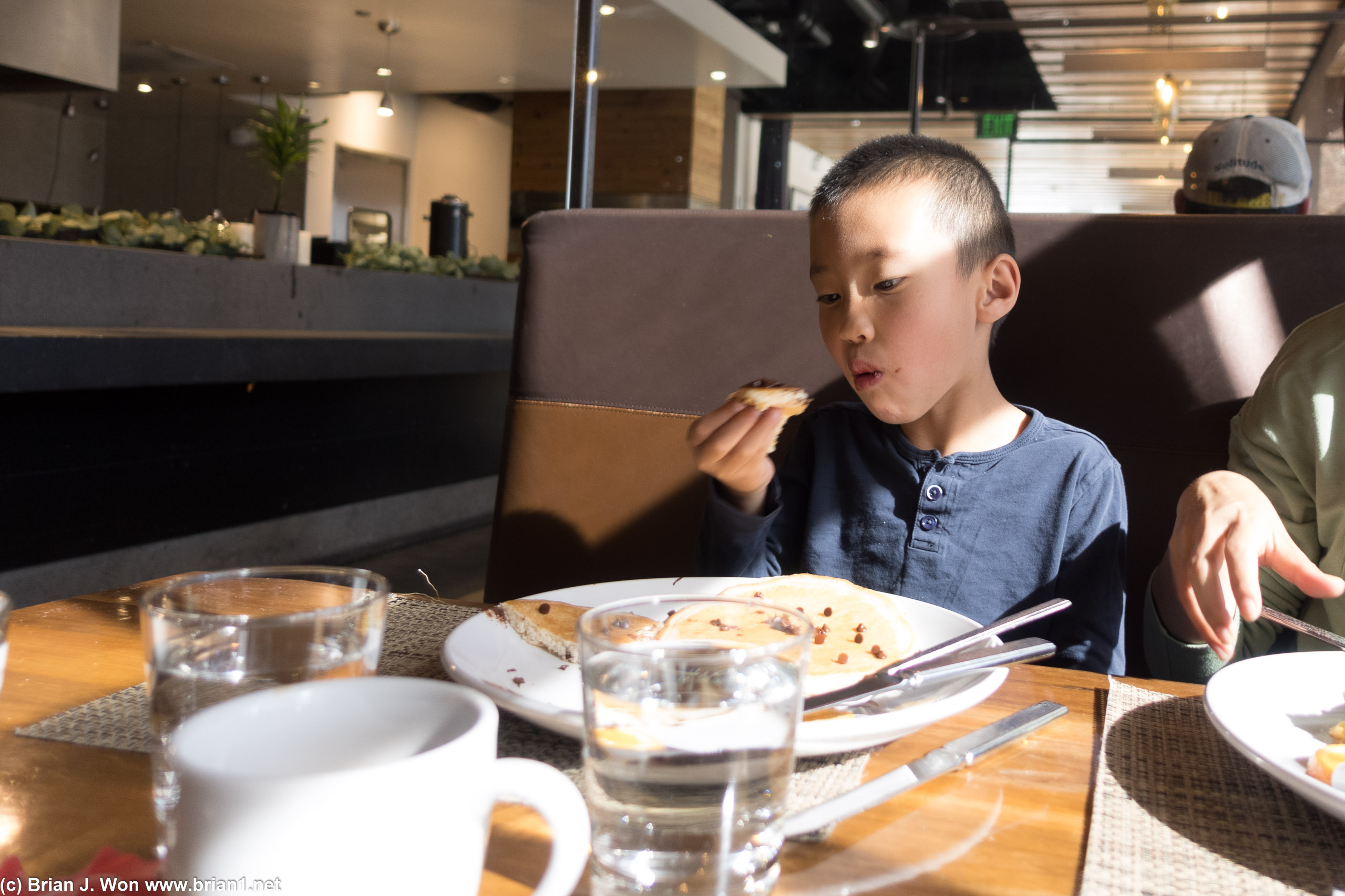 Eating chocolate chip pancakes with his hands.