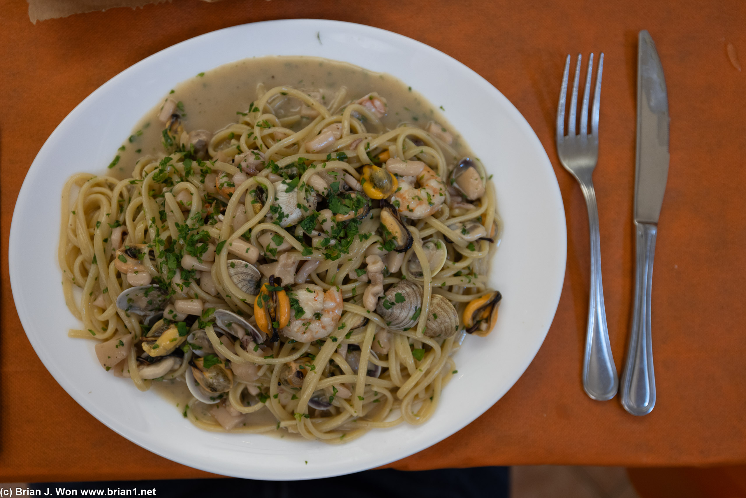 Big mound of pasta and small bits of seafood.