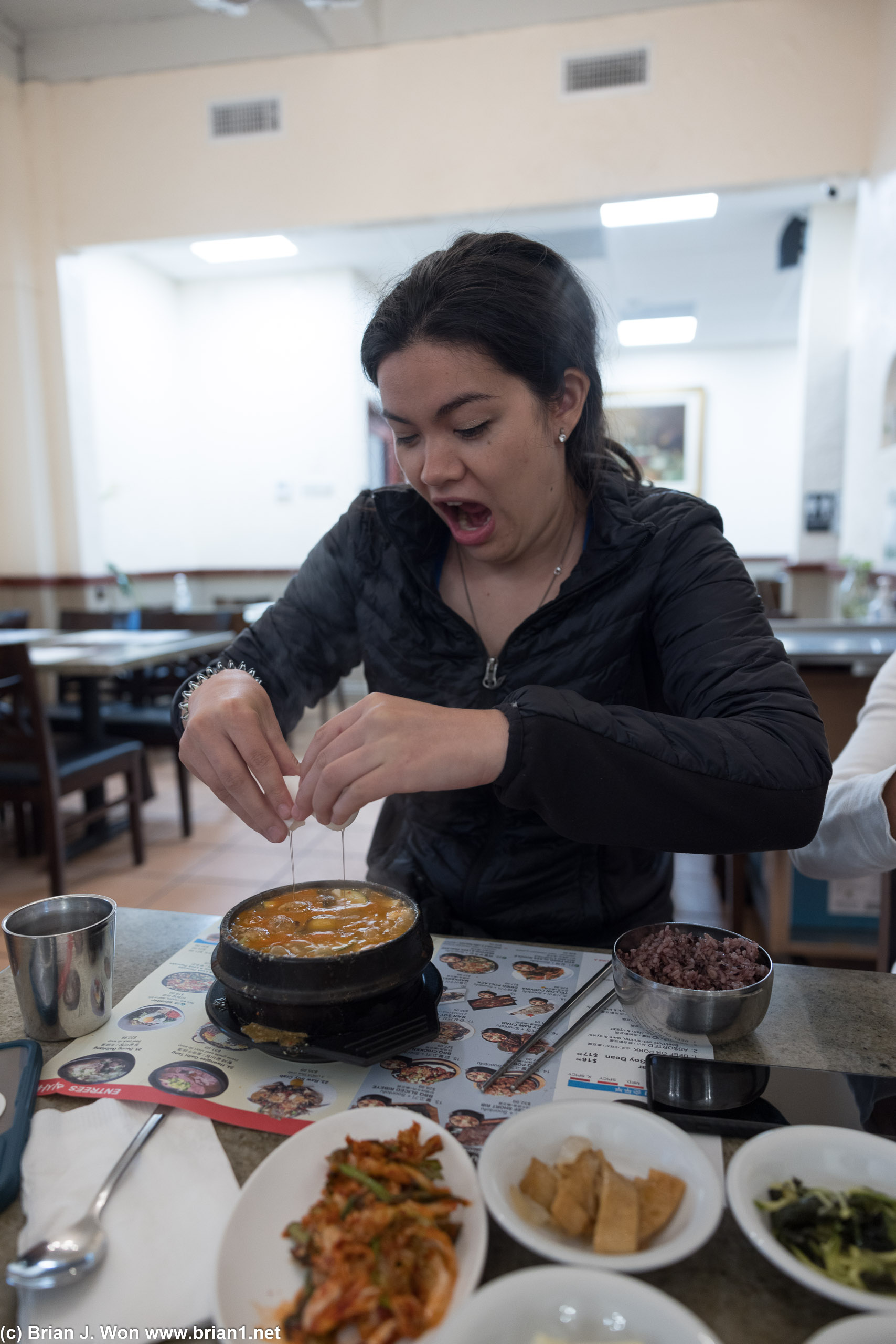 Cracking an egg into her tofu at Surawon Tofu House.