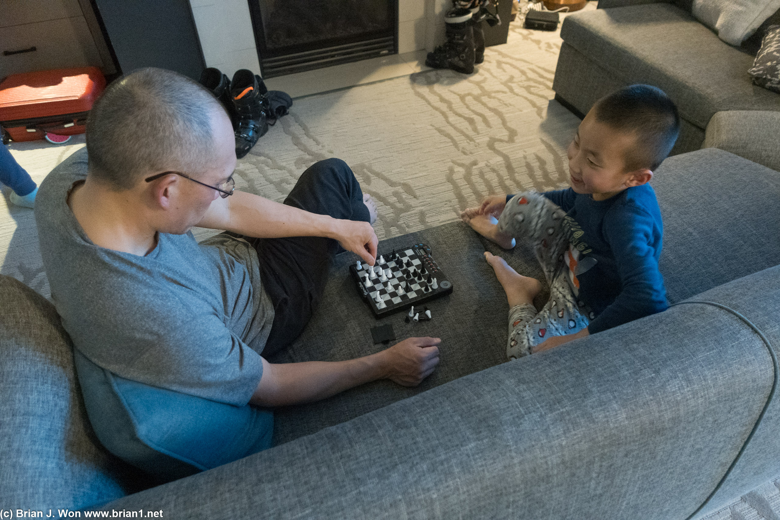 Father teaching his son chess.