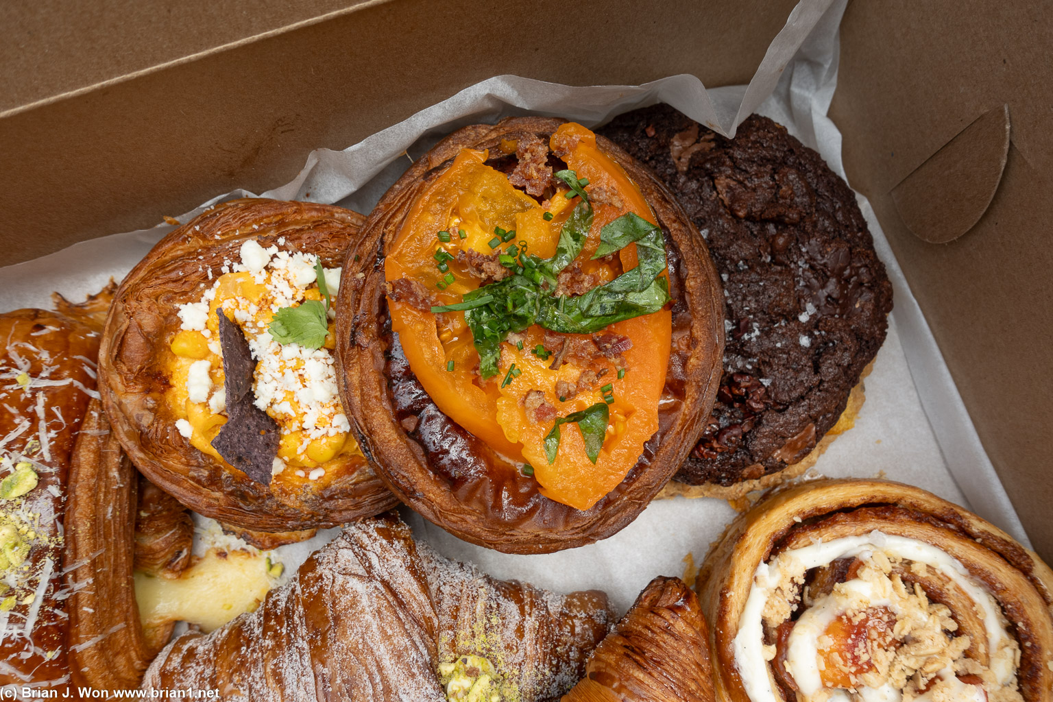 Heirloom BLT danish atop the elote corn croissant and double chocolate espresso chocolate chip, with the peach cobbler swirl below.